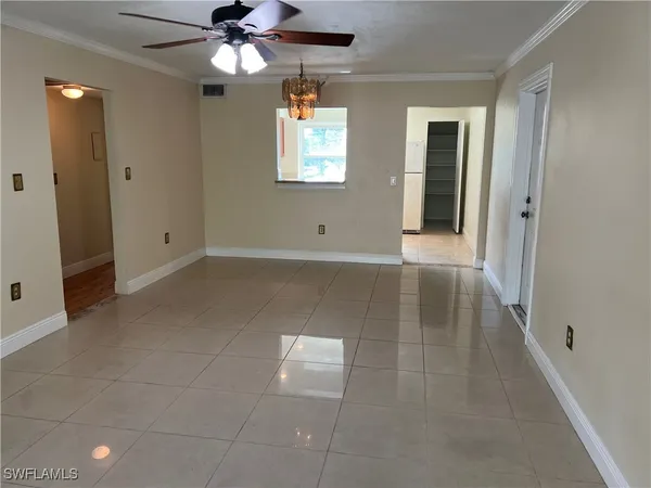 a view of an empty room with window and chandelier fan