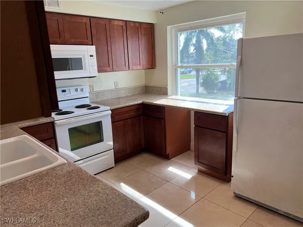 a kitchen with granite countertop a stove a microwave and a refrigerator