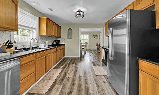 a kitchen with stainless steel appliances a refrigerator sink and wooden floor
