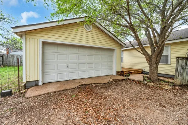 a view of a house with a small yard and large trees