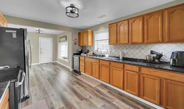 a kitchen with stainless steel appliances granite countertop a sink dishwasher stove top oven and cabinets with wooden floor