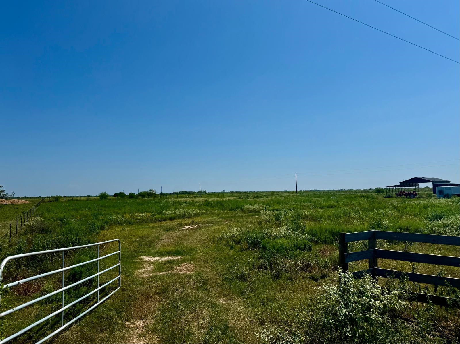 a view of a green field with wooden fence