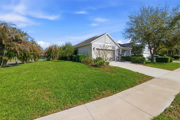 a view of a house with a big yard plants and large trees