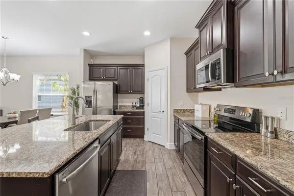 a kitchen with stainless steel appliances granite countertop a sink stove microwave and refrigerator