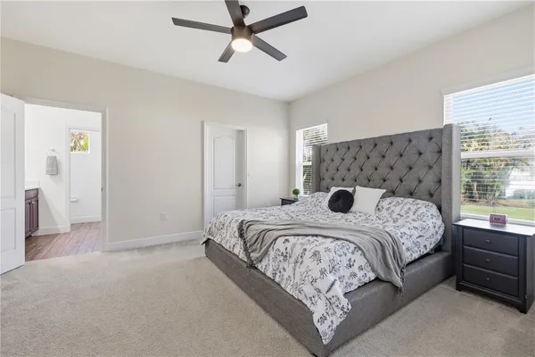 a bedroom with a large bed and a chandelier fan