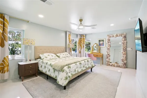 a spacious bedroom with a bed chandelier and a flat screen tv