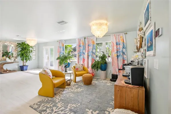 a living room with patio furniture and a potted plant