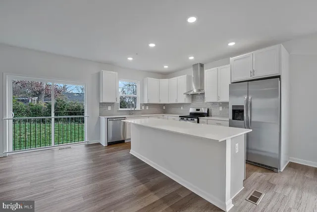 a view of kitchen with stainless steel appliances granite countertop cabinets and wooden floor