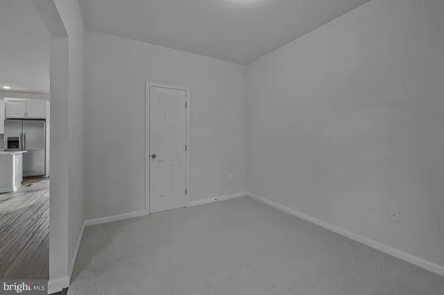 a view of an empty room with closet and mirror