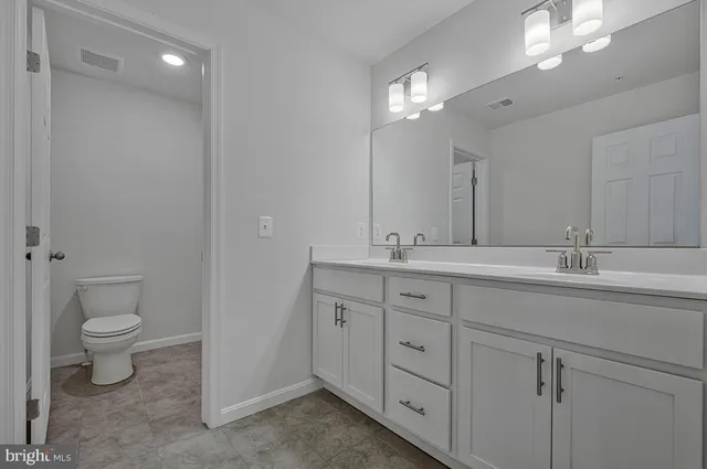 a bathroom with double vanity sink a vanity and a large mirror