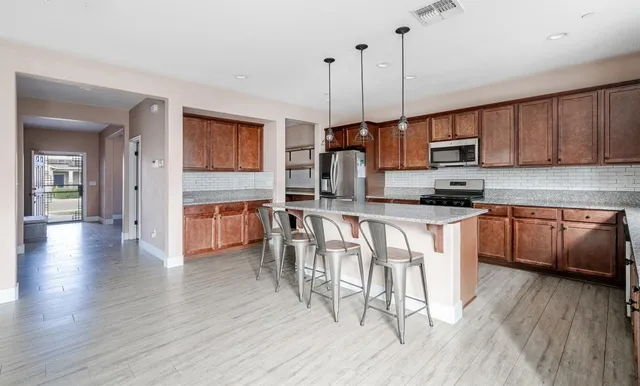 a kitchen with stainless steel appliances granite countertop wooden floors a stove and a refrigerator