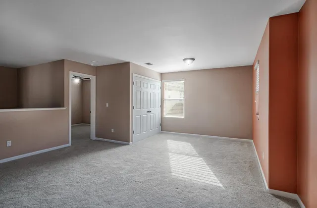 an empty room with a window and a fan