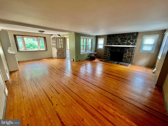 a view of empty room with wooden floor and fireplace
