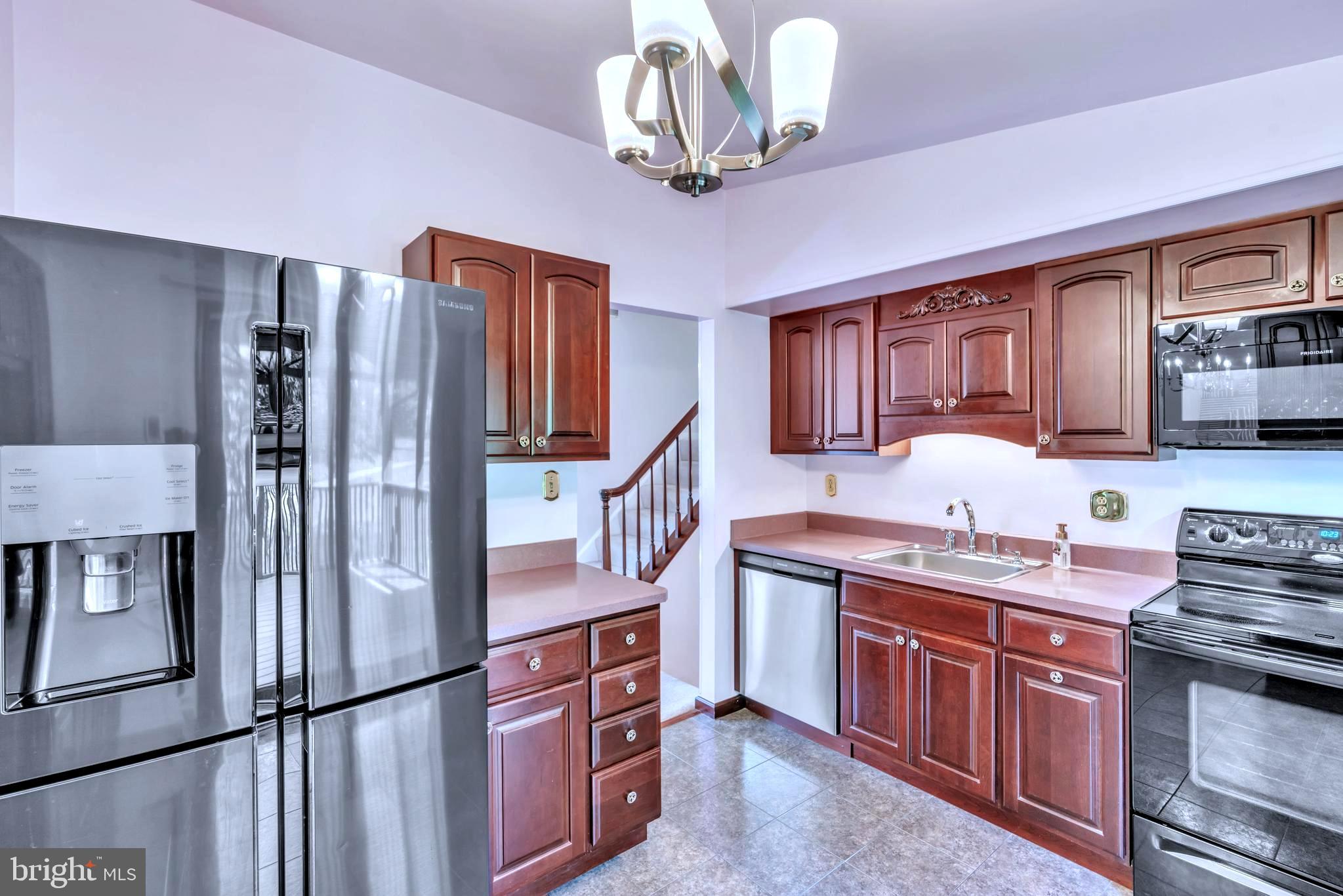 6411 Sunset Light Columbia, MD 21045 - Photo 13 of 37 a kitchen with stainless steel appliances granite countertop a refrigerator a stove a sink dishwasher a dining table and chairs with wooden floor