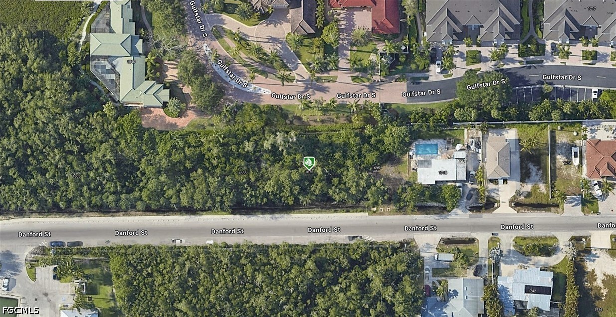 1675 Danford Street Naples, FL 34112 - Photo 2 of 3 a view of building with large trees and cars parked in front of it