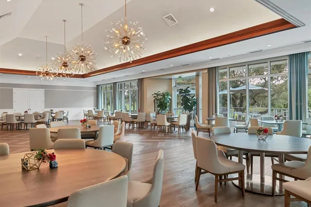 a room with lots of tables a large window and chairs