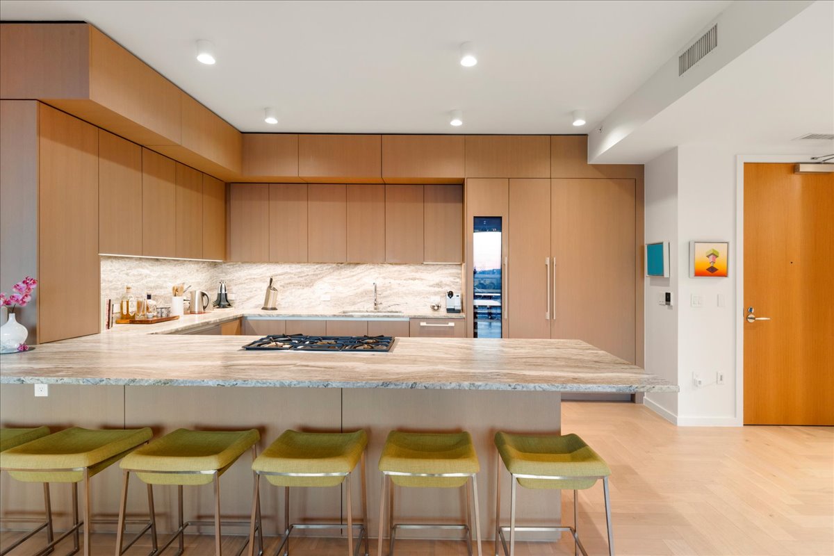 313 West 17th Street, Unit 1104 Austin, TX 78701 - Photo 10 of 40 A custom Rhode Partners kitchen crafted for Omakase-style dining, featuring a full Gaggenau® appliance suite, 3cm Fantasy Brown marble counters and backsplash, and an oversized island with steel-reinforced overhangs that comfortably seat eight. Integrated cabinetry conceals refrigeration and storage, creating a clean, contemporary backdrop for both cooking and entertaining.