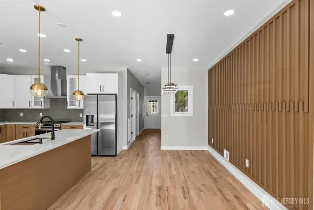 a kitchen with stainless steel appliances granite countertop a refrigerator a sink dishwasher a stove and white countertops with wooden floor