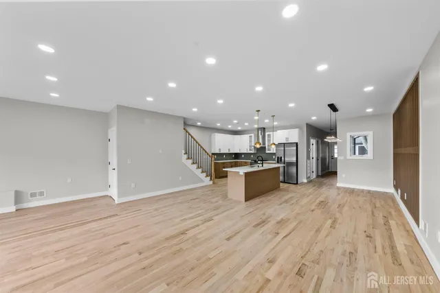 a view of kitchen with kitchen island wooden floor center island and stainless steel appliances