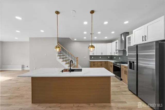 a kitchen with stainless steel appliances kitchen island granite countertop a sink a stove and a refrigerator