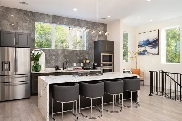 a kitchen with stainless steel appliances granite countertop a table chairs refrigerator and sink