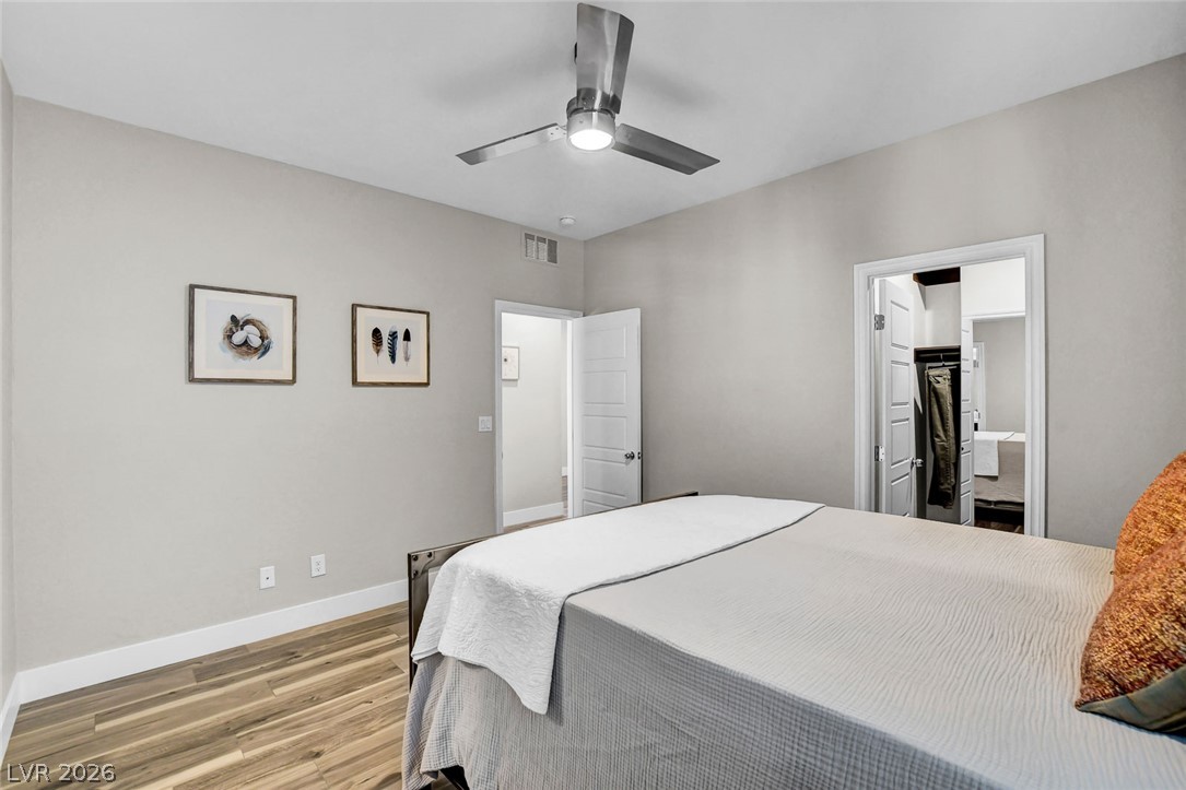 9688 Rankin Rdg Court Las Vegas, NV 89178 - Photo 28 of 53 Natural light illuminates a modern bedroom with a ceiling fan and elegant wood flooring.