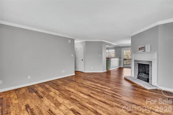 a view of empty room with wooden floor and fireplace