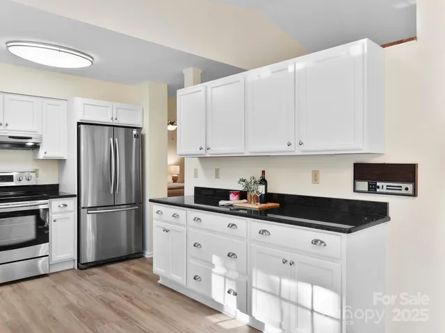a kitchen with granite countertop white cabinets and stainless steel appliances