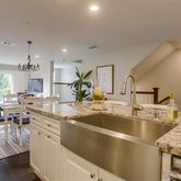 a kitchen with stainless steel appliances granite countertop a sink dishwasher a stove and a dining table with wooden floor