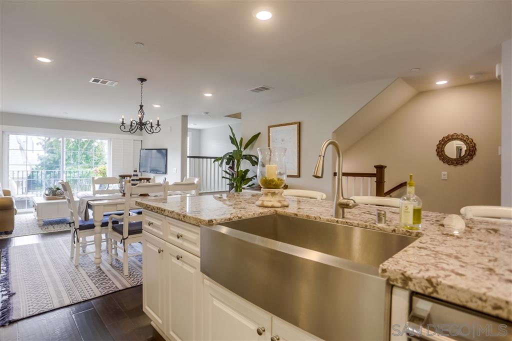 a kitchen with stainless steel appliances granite countertop a sink dishwasher a stove and a dining table with wooden floor