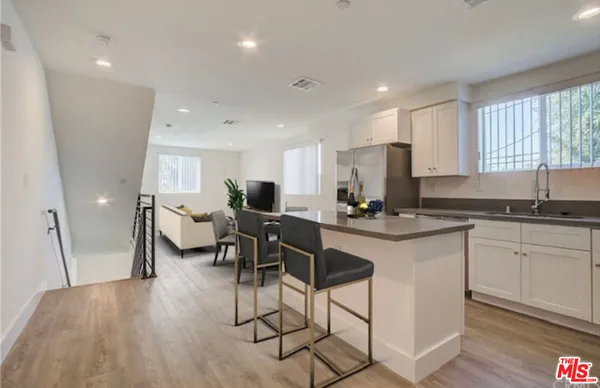 a kitchen with stainless steel appliances granite countertop a stove a sink a refrigerator and chairs