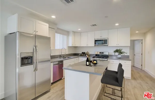 a kitchen with a refrigerator a stove a sink a dining table and chairs