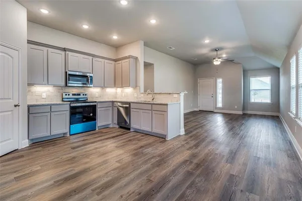 a kitchen with stainless steel appliances granite countertop a stove top oven a sink dishwasher and a oven with wooden floors