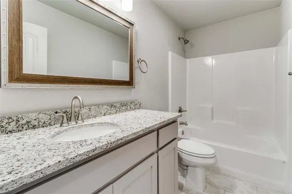 a bathroom with a granite countertop sink a toilet and a mirror