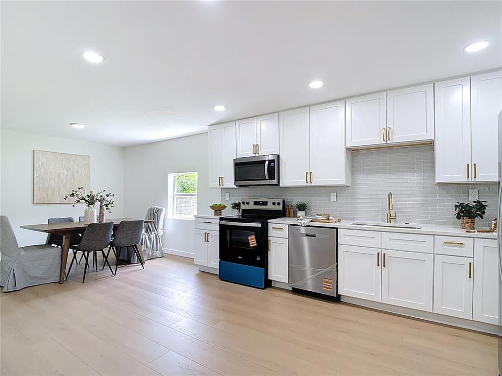 2402 East 148th Avenue Lutz, FL 33549 - Photo 18 of 71 a kitchen with stainless steel appliances kitchen island granite countertop a stove top oven a sink a dining table and chairs with wooden floor