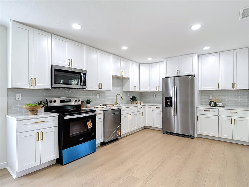 2402 East 148th Avenue Lutz, FL 33549 - Photo 21 of 71 a kitchen with stainless steel appliances granite countertop a refrigerator stove a sink dishwasher and microwave with wooden cabinets