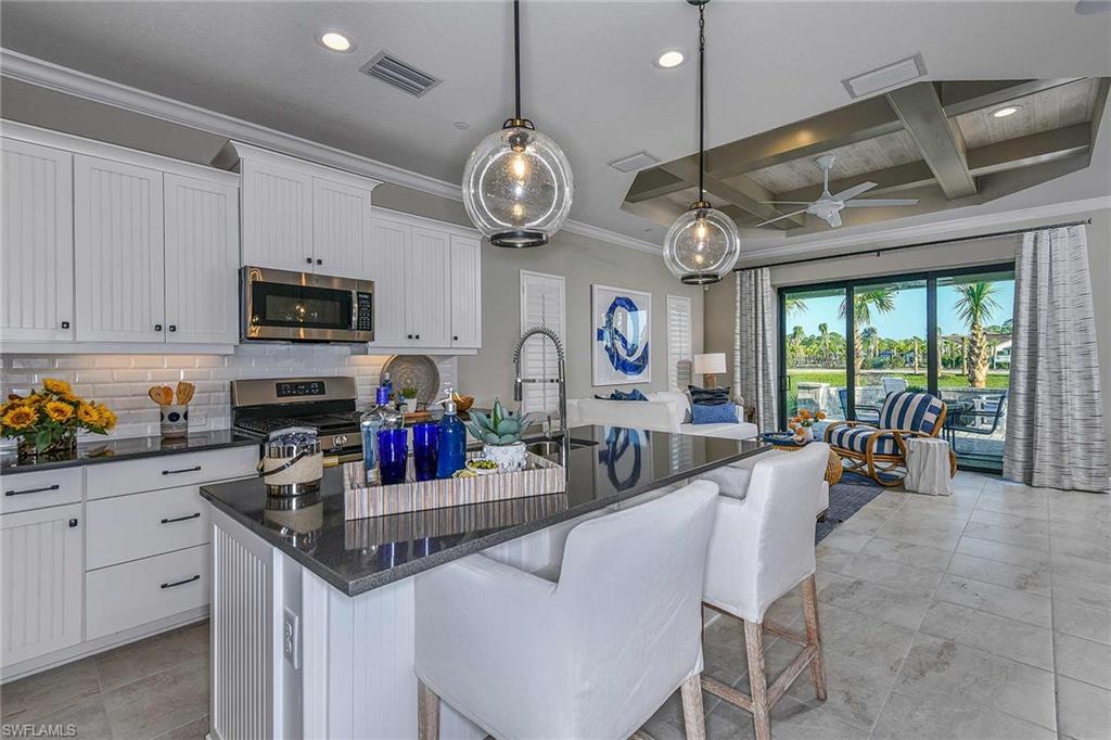 4671 Centaurus Circle Naples, FL 34120 - Photo 2 of 21 a kitchen with stainless steel appliances granite countertop a stove and a view of dining table chairs