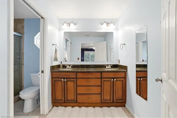 a bathroom with a granite countertop sink a toilet and a mirror