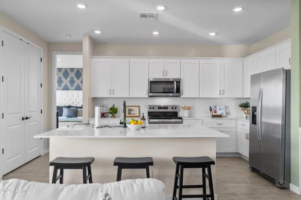 a kitchen with stainless steel appliances granite countertop a dining table chairs refrigerator and sink
