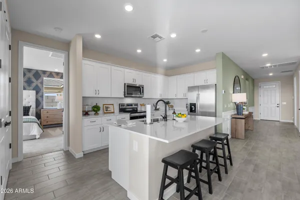 a kitchen with stainless steel appliances a refrigerator a stove a sink a dining table and chairs