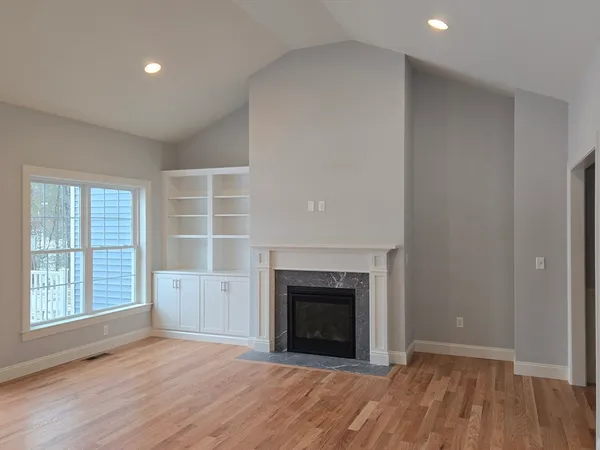 an empty room with wooden floor a fireplace and windows