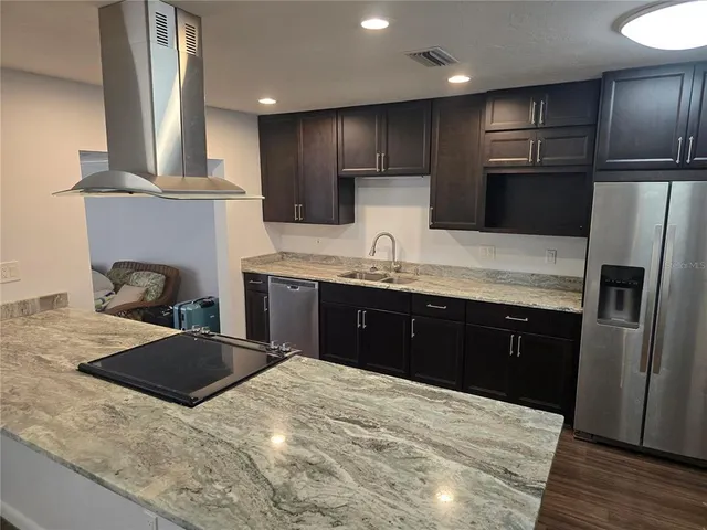 a kitchen with stainless steel appliances kitchen island granite countertop a refrigerator a sink and a stove