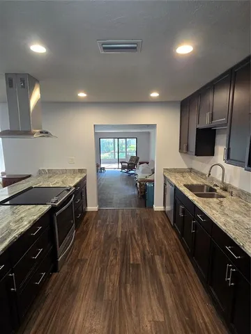 a large kitchen with granite countertop a stove top oven a sink dishwasher a dining table and chairs with wooden floor