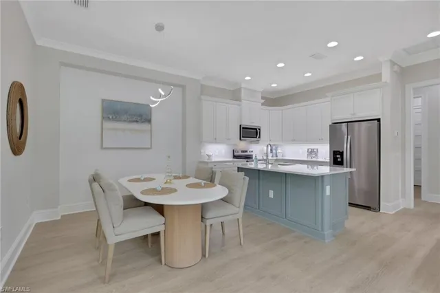 a kitchen with stainless steel appliances a sink a stove a refrigerator with white cabinets