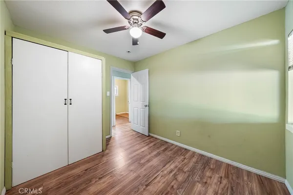 an empty room with wooden floor fan and windows