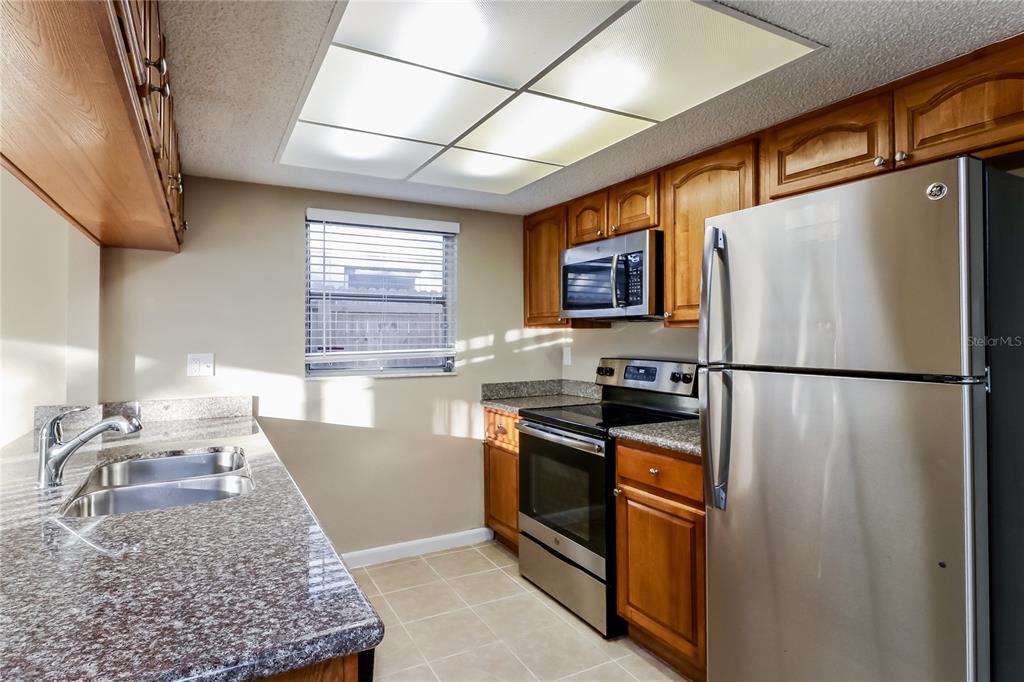 8653 Sabal Way Port Richey, FL 34668 - Photo 6 of 16 a kitchen with stainless steel appliances granite countertop a refrigerator stove a sink and dishwasher