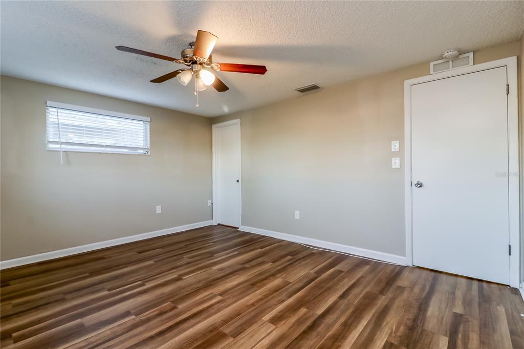 8653 Sabal Way Port Richey, FL 34668 - Photo 8 of 16 a view of an empty room with wooden floor and a ceiling fan