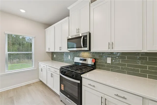 a kitchen with stainless steel appliances white cabinets and a stove top oven