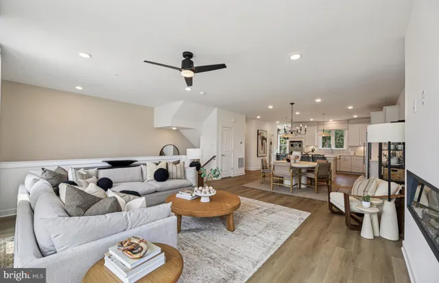 a view of a dining room and livingroom with furniture wooden floor a rug a flat screen tv a painting and a chandelier
