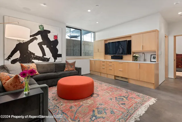 a view of an empty room with wooden floor and a kitchen